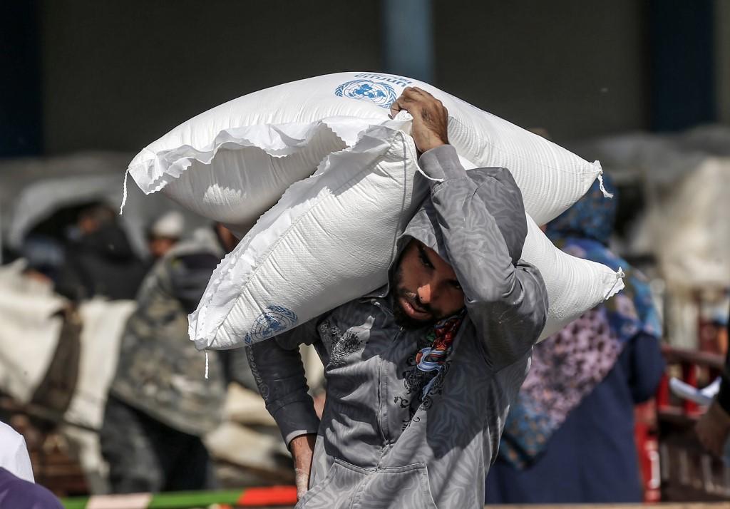 فلسطيني يحمل على كتفه أكياس دقيق تسلمها من مركز توزيع تابع لوكالة غوث وتشغيل اللاجئين الفلسطينيين (أونروا) في مخيم رفح للاجئين في جنوب قطاع غزة. 17/11/2019. سعيد خطيب / أ ف ب