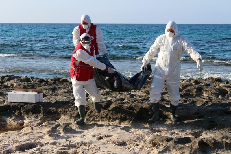 صورة أرشيفية لعمال ينتشلون جثة مهاجر غرق في البحر. (رويترز)
