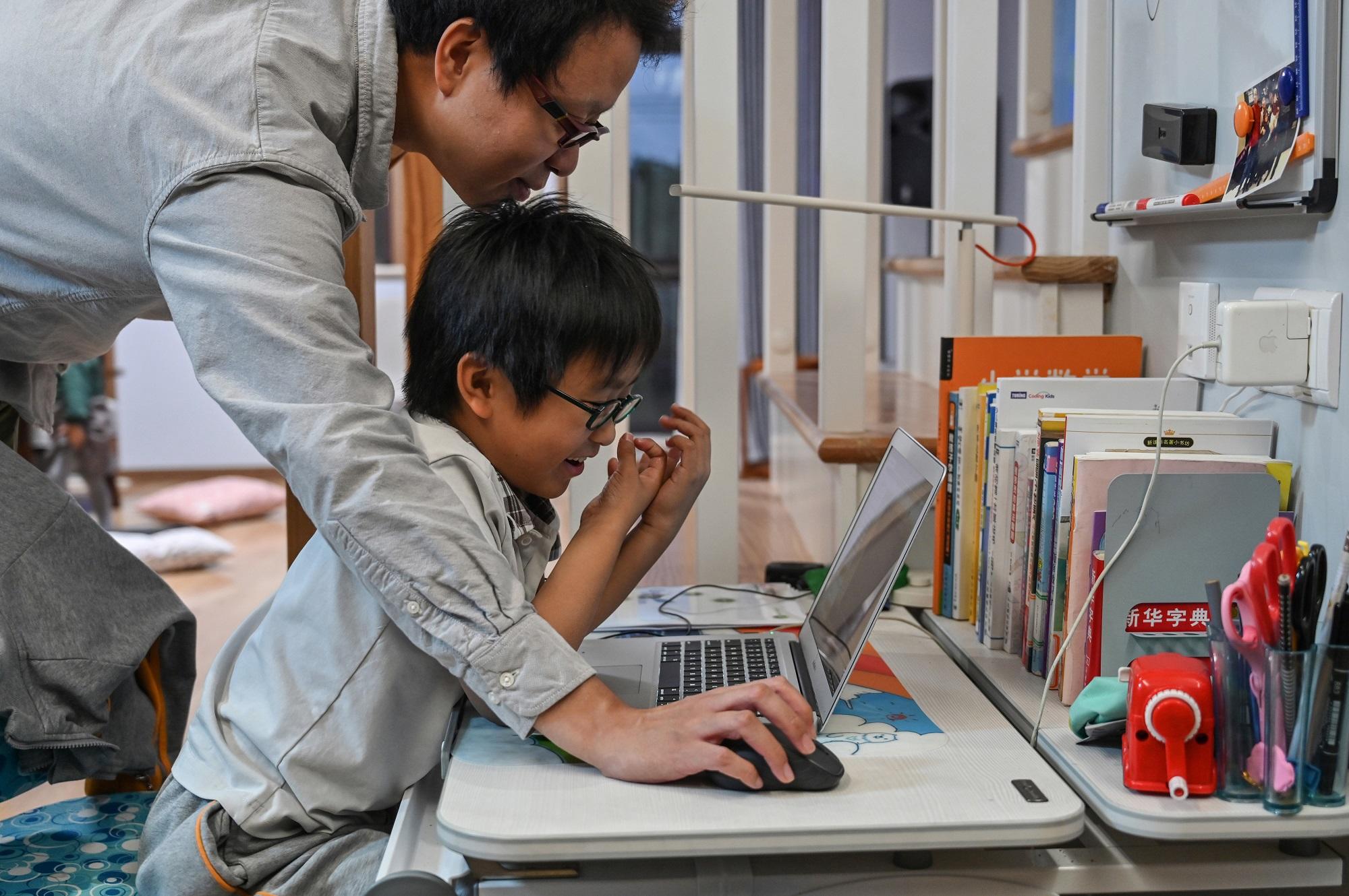زوو زينغ يساعد ابنه الذي يحمل اسم فيتا على إنشاء لعبة بها ترميز على كمبيوتره في منزله في شنغهاي. 7 تشرين ثاني/ نوفمبر 2019. هيكتور ريتامال / أ ف ب