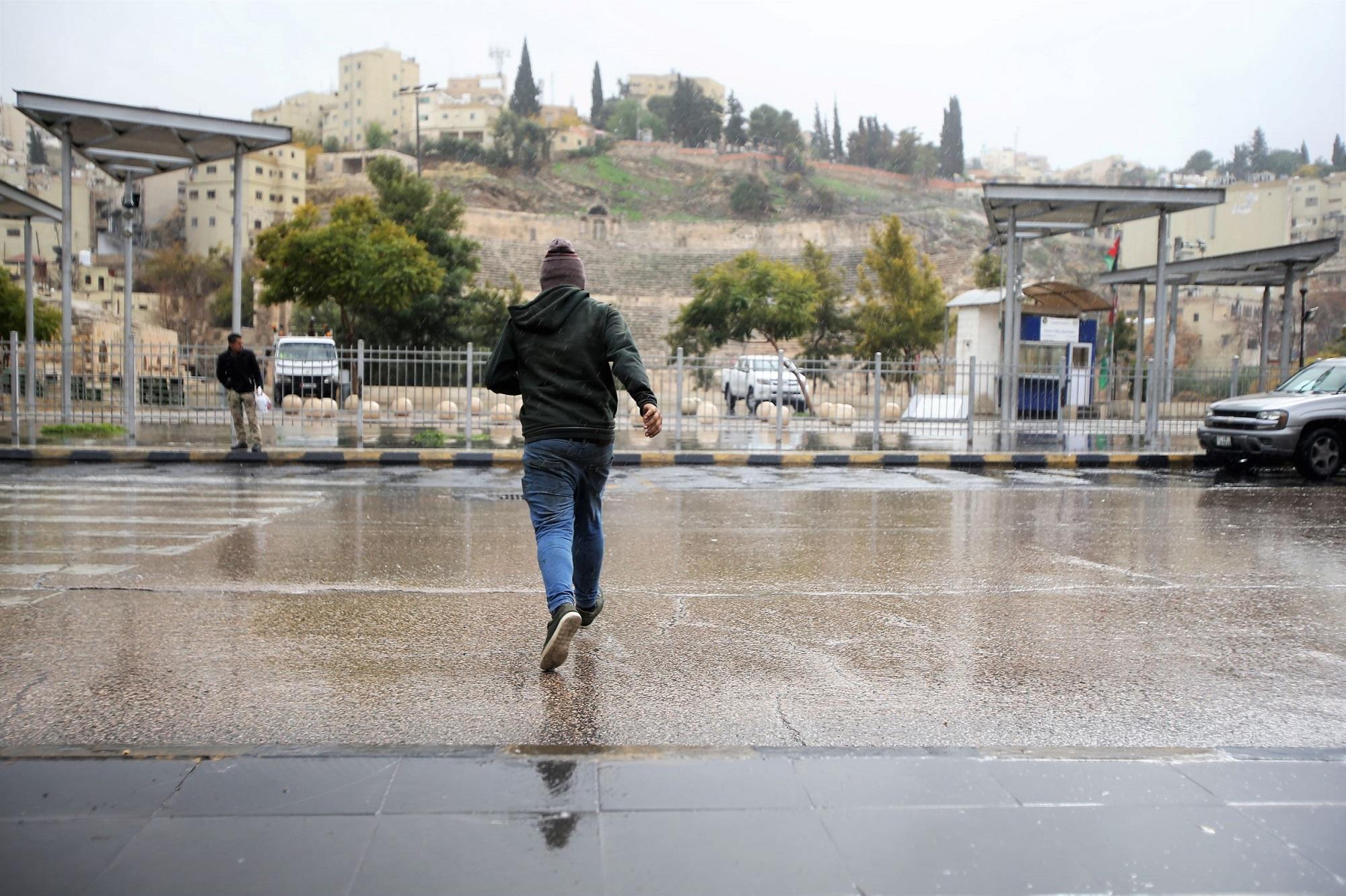 شاب يعبر الشارع خلال هطول للأمطار قرب الساحة الهاشمية في عمّان، 26/12/2019. (صلاح ملكاوي/ المملكة)