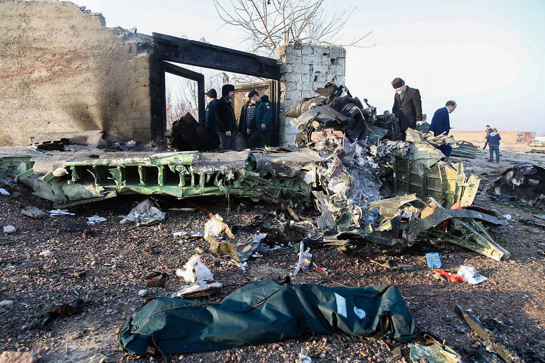 أشخاص يقفون بالقرب من الحطام بعدما تحطمت طائرة أوكرانية تقل 176 راكباً بالقرب من مطار الإمام الخميني في طهران. 8 يناير 2020. (أ ف ب)