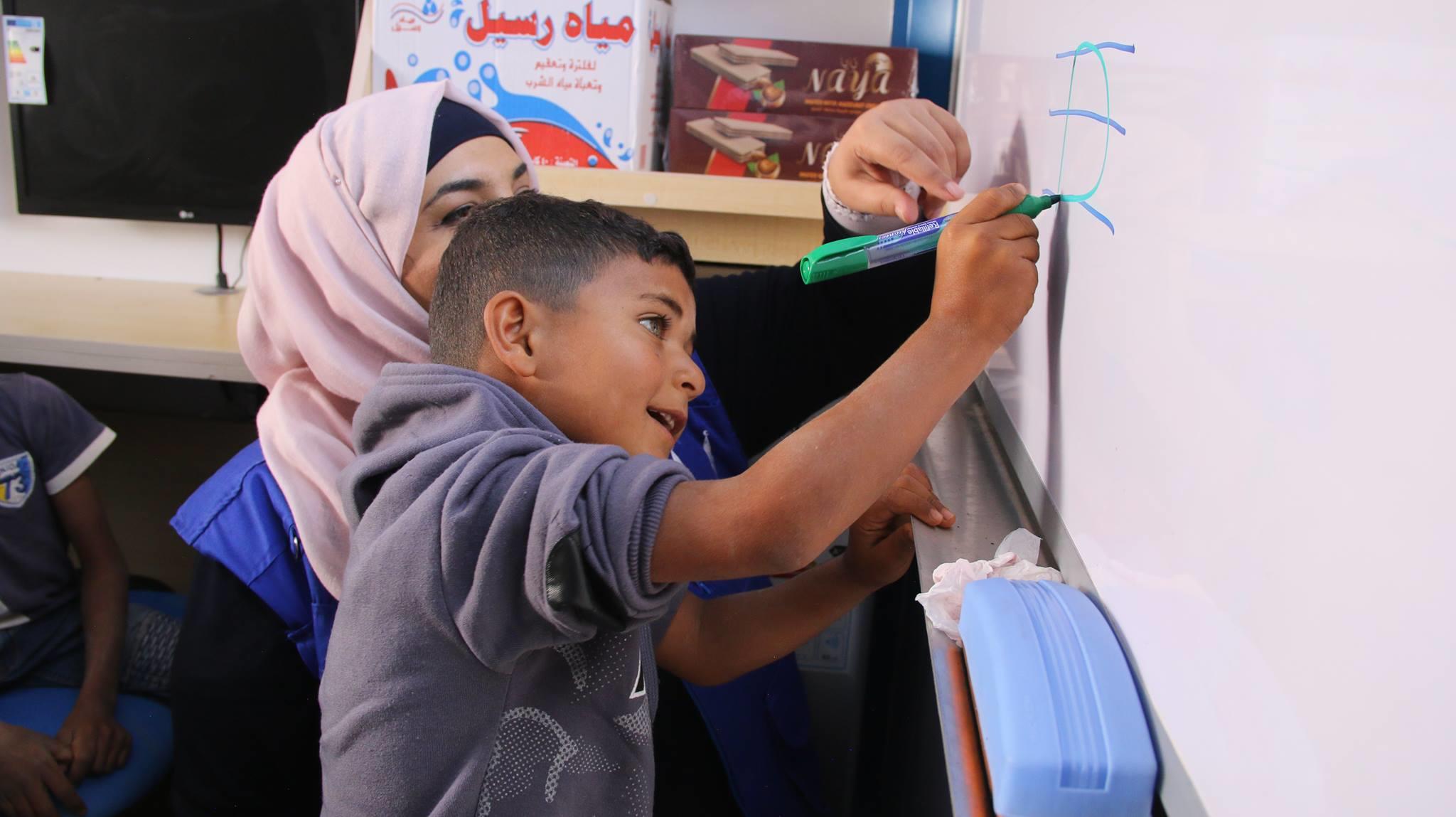 طفل سوري يتعلم الكتابة في حافلة تعليمية متنقلة في المفرق شمالي الأردن. (منظمة الإغاثة الإسلامية/ من صفحة مفوضية الأمم المتحدة لشؤون اللاجئين)