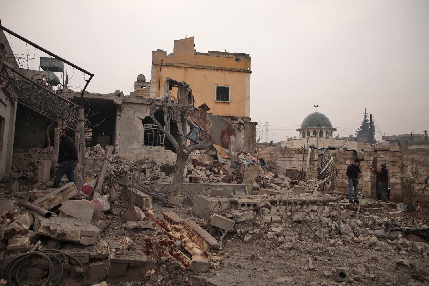 سوري يقف أمام منزله الذي انهار بعد قصف للحكومة. (أ ف ب)