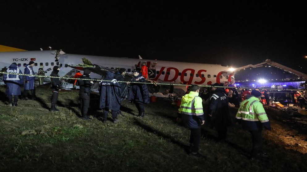 أفراد أمن يطوقون موقع تحطم طائرة بعد أن انزلقت من المدرج عند هبوطها في مطار صبيحة كوكجن في إسطنبول. 5 فبراير 2020. (أ ف ب)