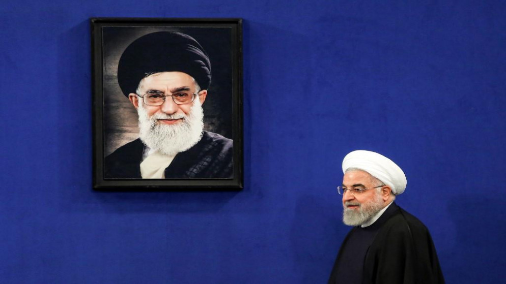 الرئيس الإيراني حسن روحاني يسير قرب صورة للمرشد الأعلى الإيراني علي خامنئي. (عطا كيناري/ أ ف ب)
