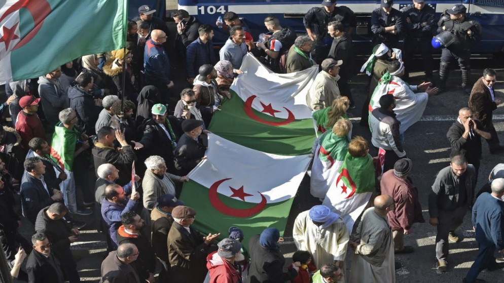 جزائريون يحملون أعلامًا وطنية كبيرة أثناء مسيرتهم في تظاهرة مناهضة للحكومة في العاصمة الجزائر في 14 فبراير 2020. رياض كرمي / أ ف ب