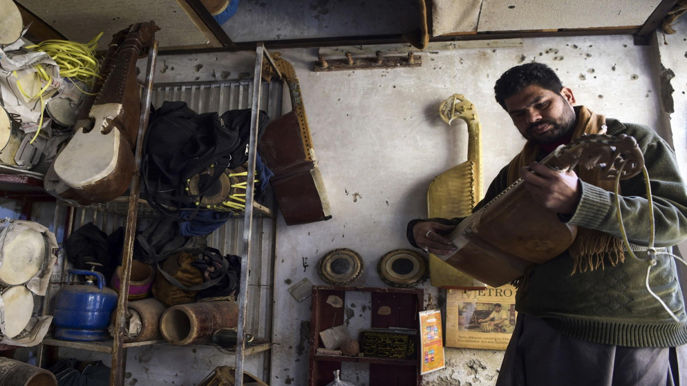 شاب باكستاني يفحص آلة موسيقية تقليدية في مكان عمله على مشارف بيشاور. 03/01/2019. (عبد المجيد / أ ف ب)