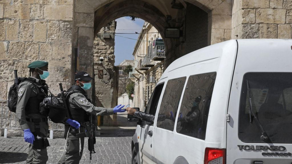  شرطة الاحتلال الإسرائيلي تفحص أوراق سائق أثناء دورية بالقرب من بوابة في البلدة القديمة في القدس ، 25 مارس ، 2020. (مناعم كاهانا / أ ف ب)