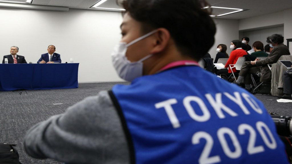 مصور يرتدي سترة لدورة الألعاب الأولمبية الصيفية بطوكيو 2020، ويرتدي قناع وجه كإجراء وقائي ضد فيروس كورونا (بهروز مهري / أ ف ب)
