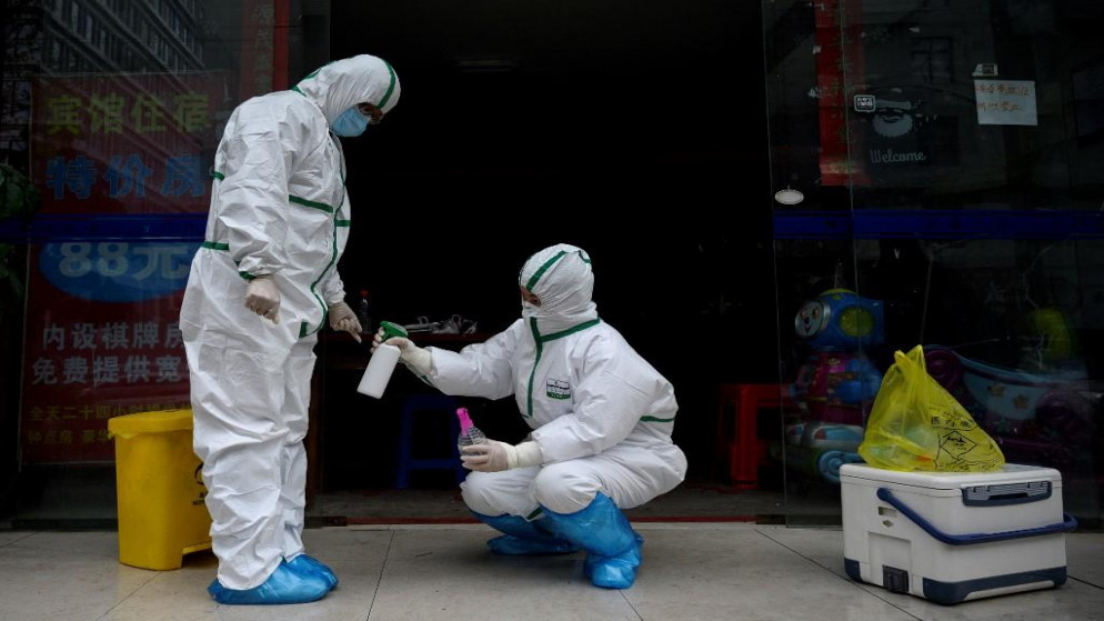 عاملة ترتدي بدلة طبية وتقوم بتطهير زميل لها في عيادة اختبار لفيروس كورونا المستجد في ووهان ، في مقاطعة هوبي وسط الصين .29 مارس 2020. (نويل سيليس / أ ف ب) 