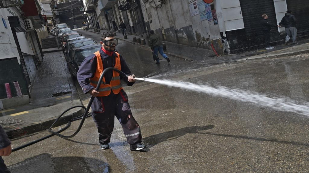عامل جزائري يغسل شارعًا في العاصمة الجزائر، خلال أزمة فيروس كورونا، 27 مارس 2020. (أ ف ب)