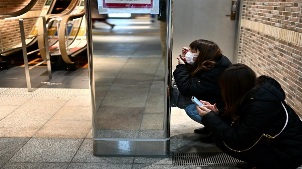 امرأة ترتدي قناع وجه، في محطة قطار جوتاندا في طوكيو، 30 مارس 2020. (أ ف ب)