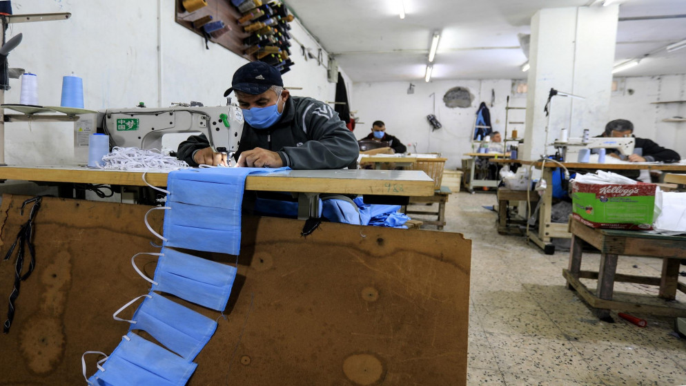 عمال فلسطينيون يصنعون بدلات وكمامات واقية في ورشة عمل في قطاع غزة. 30/03/2020. (محمود حمص/ أ ف ب)