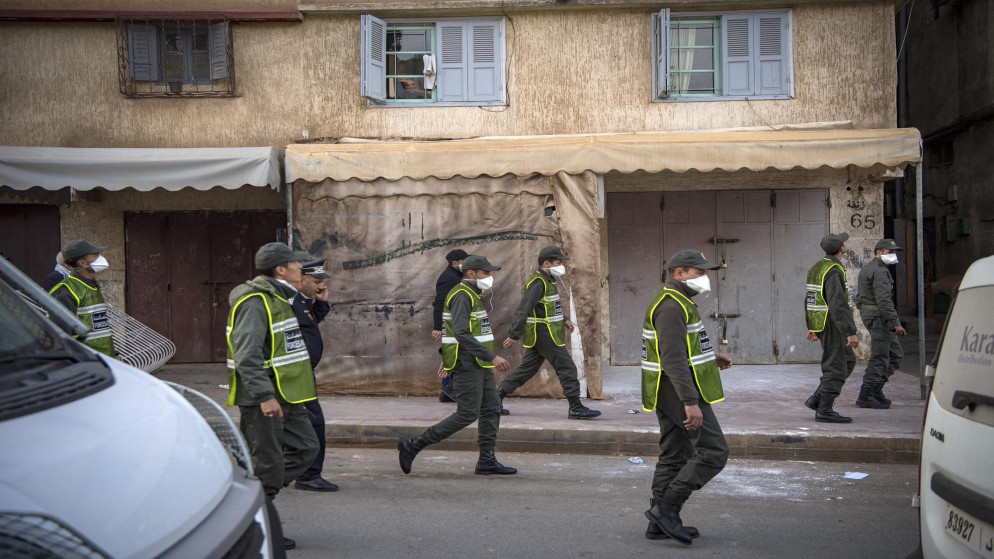 أفراد من قوات تابعة لوزارة الداخلية المغربية يسيرون على طول شارع في حي تكادوم في العاصمة الرباط لإدخال الناس إلى منازلهم للوقاية من فيروس كورونا. 27/03/2020. (فضل سينا / أ ف ب)