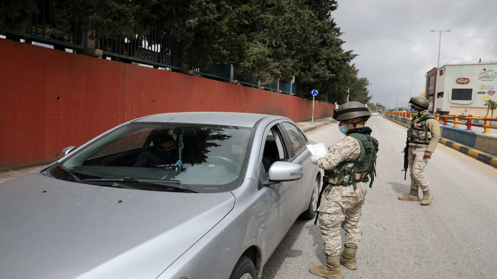 أفراد من القوات المسلحة يدققون على تصريح مرور ورقي لمركبة خلال حظر تجول فرضته الحكومة الأردنية لمواجهة فيروس كورونا. 28/03/2020. (محمد حامد / رويترز)