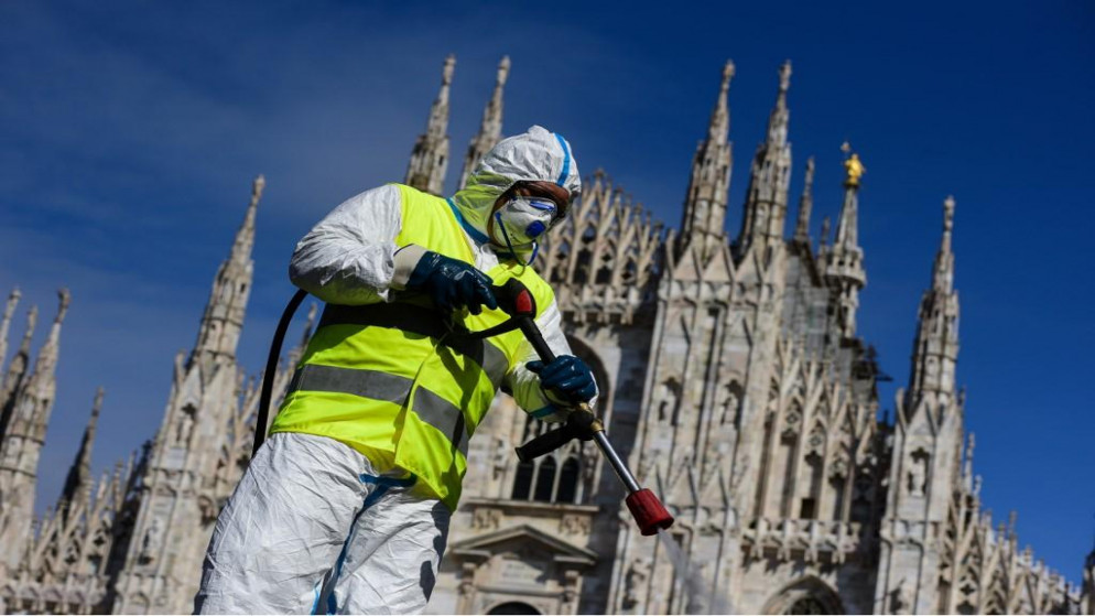 موظف يرتدي ملابس واقية يعمل في شركة خدمات بيئية يرش معقمات في ساحة دومو في ميلانو للوقاية من فيروس كورونا. 31/03/2020. (بييرو كروسياتتي / أ ف ب)
