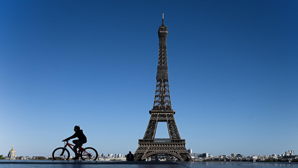 فتى على دراجة هوائية بالقرب من برج إيفيل في العاصمة الفرنسية باريس. (أ ف ب)