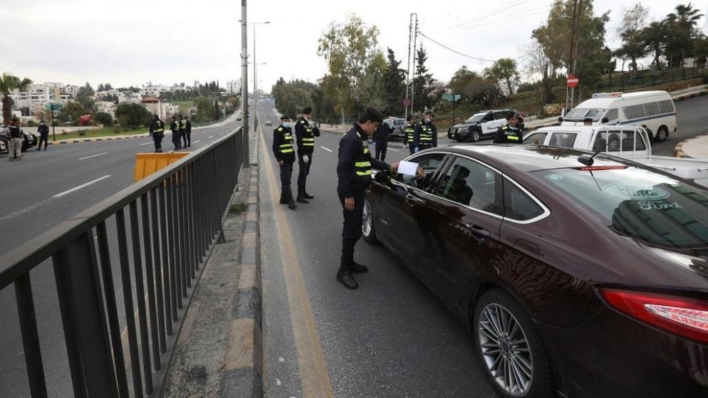 رجل أمن عام يتفقد تصريحاً ورقياً لسائق مركبة في مدينة عمّان خلال حظر التجول، 22 آذار/مارس 2020. (محمد حامد/ رويترز)