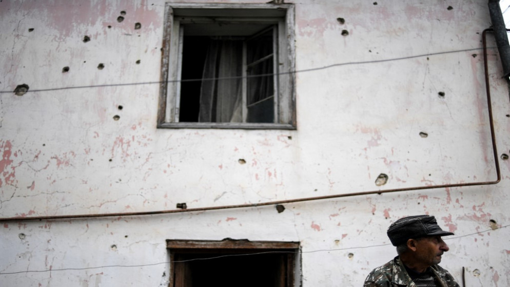 شخص يقف أمام منزل تعرض لإطلاق نار في ناغورني كارباخ حيث تدور اشتباكات بين أرمينيا وأذربيجان. (أ ف ب)