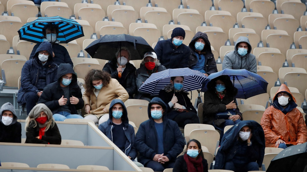 مشجعون يحملون مظلات خلال مباراة ربع النهائي، بطوله فرنسا المفتوحة لكرة المضرب، بين الأرجنتيني دييجو شوارتزمان والنمساوي دومينيك ثيم، باريس، فرنسا، 6 أكتوبر 2020. (رويترز)