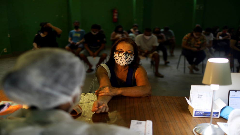 ممرضة تأخذ عينة دم من امرأة لاختبار فيروس كورونا، في سانتا حي مارتا الفقير في ريو دي جانيرو بالبرازيل، 9 أكتوبر / تشرين الأول 2020. (رويترز)