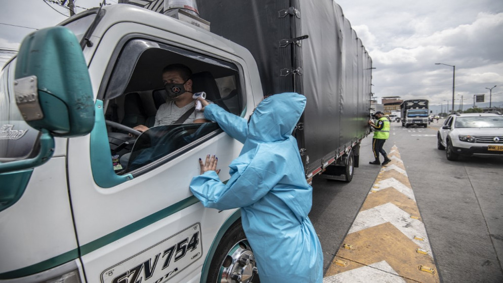عامل يفحص درجة حرارة جسم سائق شاحنة وسط جائحة فيروس كورونا الجديد، جنوب بوغوتا، 6 أكتوبر 2020. (أ ف ب)