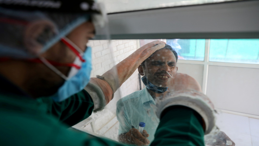 عامل في القطاع الصحي يجمع عينة مسحة من رجل وسط انتشار فيروس كورونا المستجد في الهند. 09/10/2020. (رويترز)
