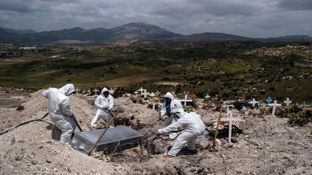 عمال في مقبرة يرتدون بدلات واقية من فيروس كورونا، في مقبرة في تيخوانا المكسيكية، 21/04/2020. (أ ف ب)