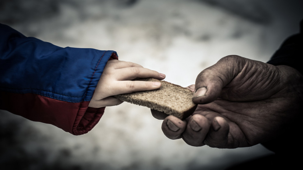 طفل يعطي شخصا محتاجا قطعة من الخبز. (shutterstock)