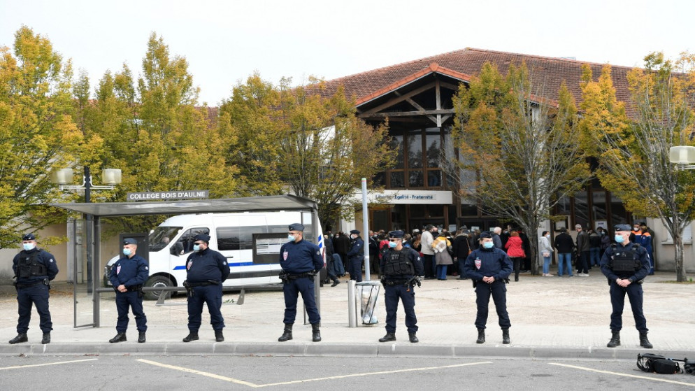 رجال أمن عند مدخل مدرسة كان يعمل فيها المدرس الذي قُتل في كونفلانس سانت أونورين شمال غرب باريس. (أ ف ب)