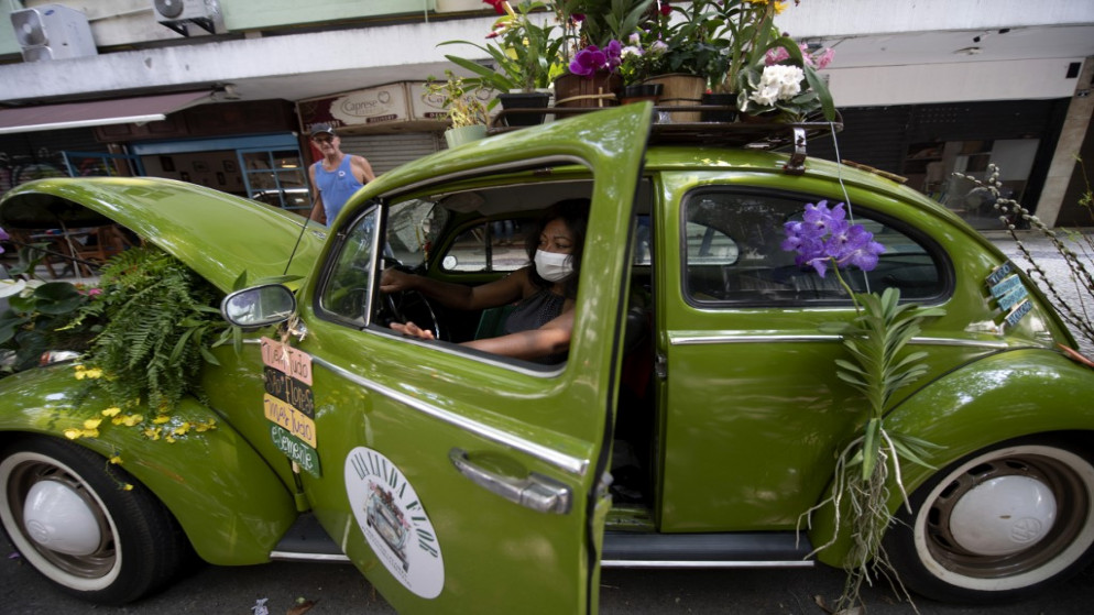 البرازيلية البالغة 51 عاما تجلس في سيارة فولكس فاجن بيتل عام 1969 التي حولتها إلى متجر زهور متنقل للنجاة من الأزمة الناجمة عن جائحة فيروس كورونا COVID-19 ، في حي كوباكابانا . 14 تشرين الأول/ أكتوبر 2020 . (ماورو بيمينتيل /أ ف ب)
