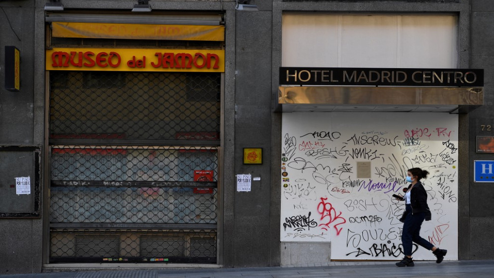 امرأة تمر أمام فندق مغلق ومطعم في شارع غران فيا الرئيسي بوسط مدريد.  16 تشرين الأول/أكتوبر 2020. (أ ف ب)