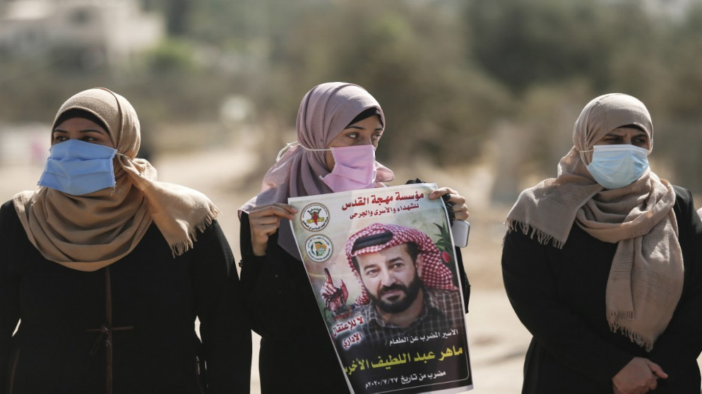 امرأة فلسطينية تحمل صورة المعتقل الفلسطيني ماهر الأخرس المضرب عن الطعام. (أ ف ب)
