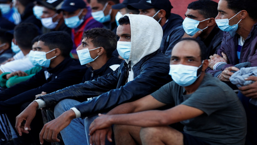 مجموعة من المهاجرين على شاطئ ماسبالوماس بعد وصول عشرات المهاجرين إلى جنوب جزيرة غران كناريا، في ماسبالوماس، إسبانيا، 20 تشرين الأول/ أكتوبر 2020. (رويترز)