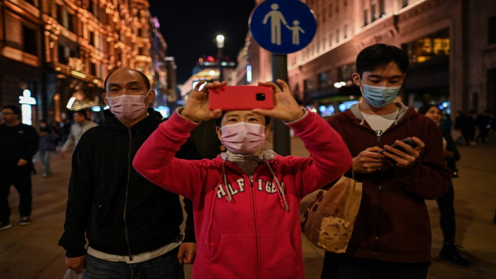 امرأة ترتدي كمامة للوجه كإجراء وقائي ضد فيروس كورونا المستجد في شارع للمشاة في شنغهاي. 23 تشرين الأول/ أكتوبر 2020. (أ ف ب)
