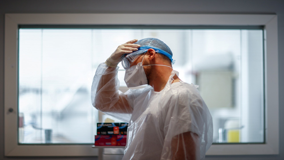معالج طبيعي يعدّل غطاء رأسه الواقي قبل البدء بعلاج مريض بفيروس كورونا المستجد في وحدة العناية المركزة في أحد مستشفيات باريس. 26/10/2020. (غونزالو فوينتيس/ رويترز)