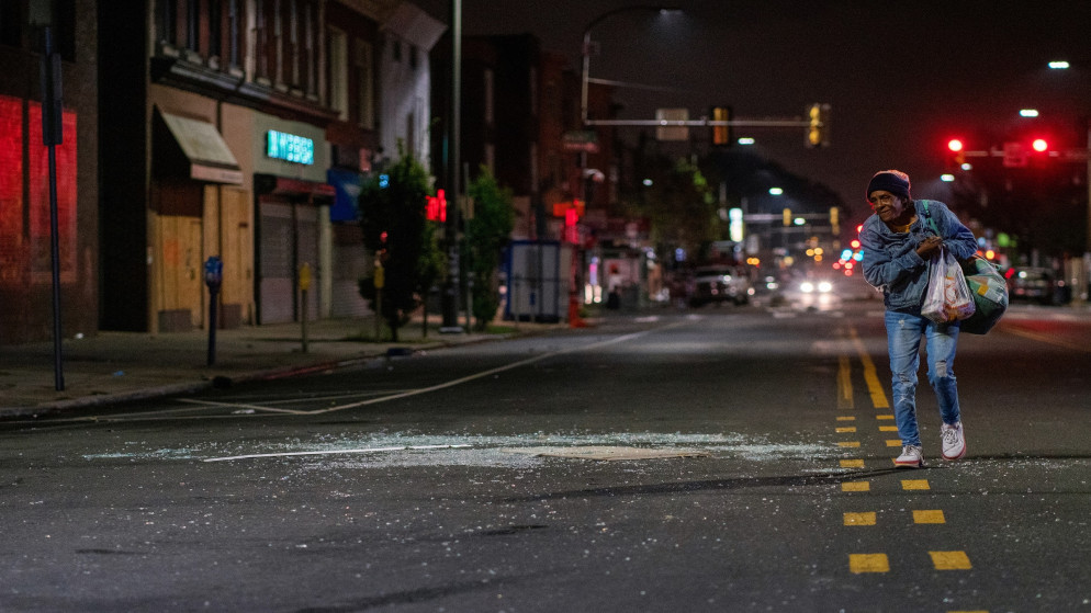 امرأة تسير في منتصف الشارع بجوار زجاج محطم من واجهة متجر بعد احتجاجات على مقتل والتر والاس في فيلادلفيا في ولاية بنسلفانيا الأميركية، 27 تشرين الأول/أكتوبر 2020. (رويترز)