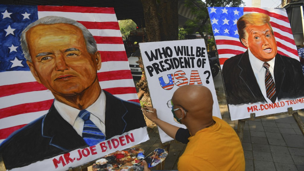 رسم صورة للمرشح الرئاسي الديمقراطي جو بايدن، بجوار صورة الرئيس الأميركي دونالد ترامب قبل الانتخابات الرئاسية الأميركية المقبلة، 29 تشرين الأول/ أكتوبر 2020. (رويترز)