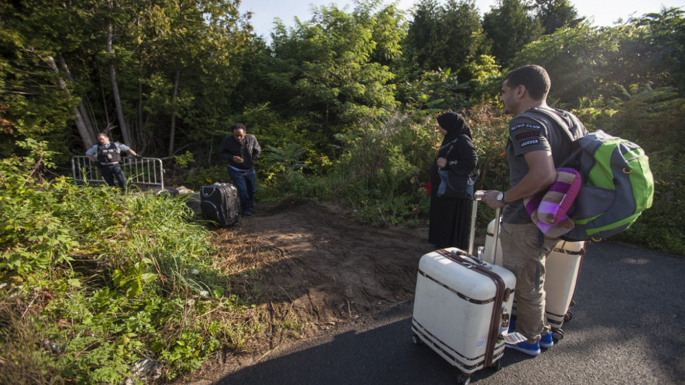 يتحدث ضباط شرطة الخيالة الملكية الكندية، مع مهاجرين أثناء استعدادهم لعبور الحدود الأميركية / الكندية بشكل غير قانوني، 20 آب/ أغسطس 2017. (رويترز)