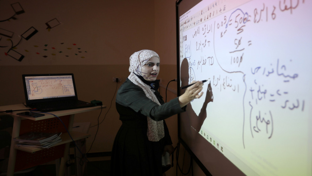 معلمة تعطي دروسا لطلابها عن بعد من أحد الغرف الصفية في أحد مدارس عمّان. (رويترز)