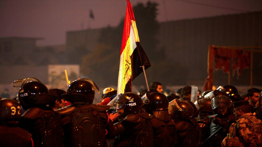محتجون عراقيون في البصرة أمامهم رجال الأمن. (أ ف ب)