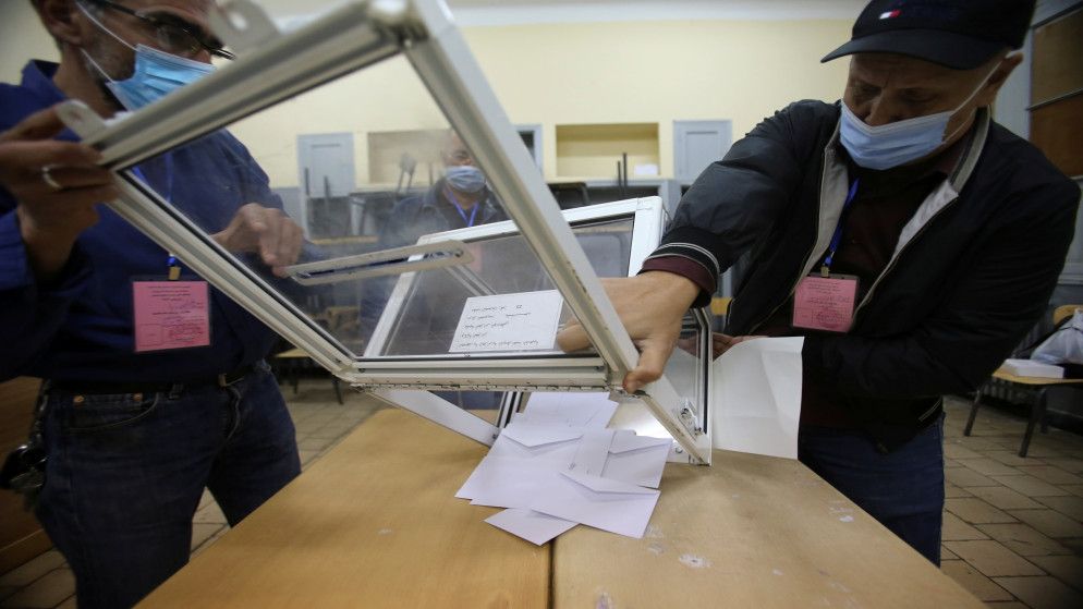 عمال في مركز انتخابات في الجزائر يفرغون صندوق اقتراع في نهاية التصويت في استفتاء على دستور جديد. 01/11/2020. (رمزي بودينا/ أ ف ب)