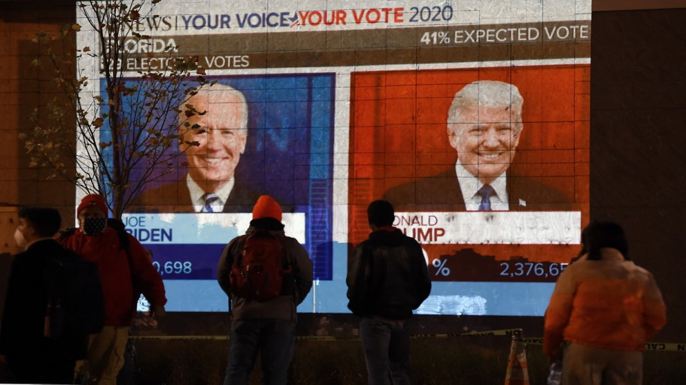 أفراد يشاهدون شاشة كبيرة تعرض نتائج الانتخابات الحية في فلوريدا في يوم الانتخابات في واشنطن. 3 تشرين الثاني/نوفمبر 2020 (أ ف ب)