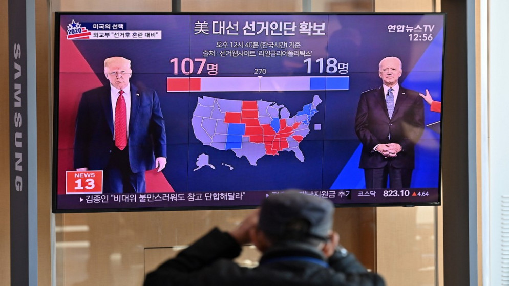 ِشخص يشاهد برنامجا تلفزيونيا يتحدث عن الانتخابات الرئاسية الأميركية ويعرض صورًا لترامب (يسار) وبايدن في سيول.  4/11/2020 (أ ف ب)