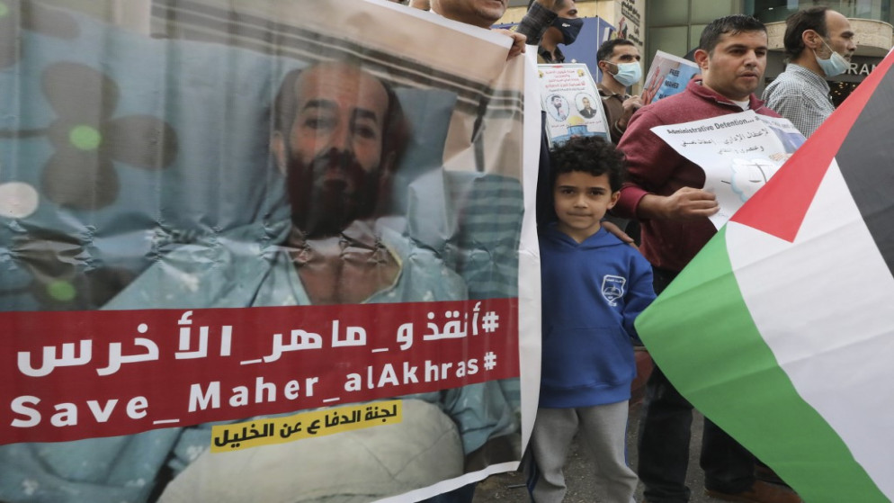 فلسطينيون يحملون لافتة كتب عليها إنقذوا ماهر الأخرس الذي كان مضربا عن الطعام. (أ ف ب)