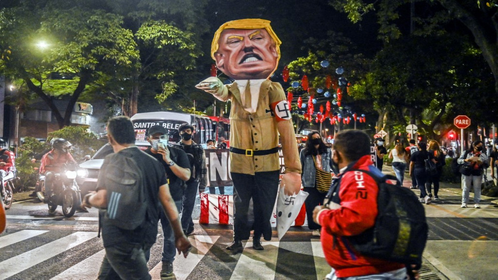 متظاهرون يحيطون بلعبة تصور رئيس الولايات المتحدة دونالد ترامب وهو يؤدي تحية نازية قبل حرقها في ميديلين ، كولومبيا ، في 6 نوفمبر 2020 . (ا ف ب)