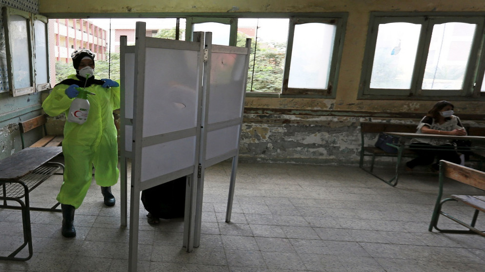 امرأة ترتدي كمامة تعقم كشك اقتراع في مدرسة تستخدم كمركز اقتراع في الجيزة المصرية، 24 تشرين الأول/ أكتوبر 2020. (رويترز)