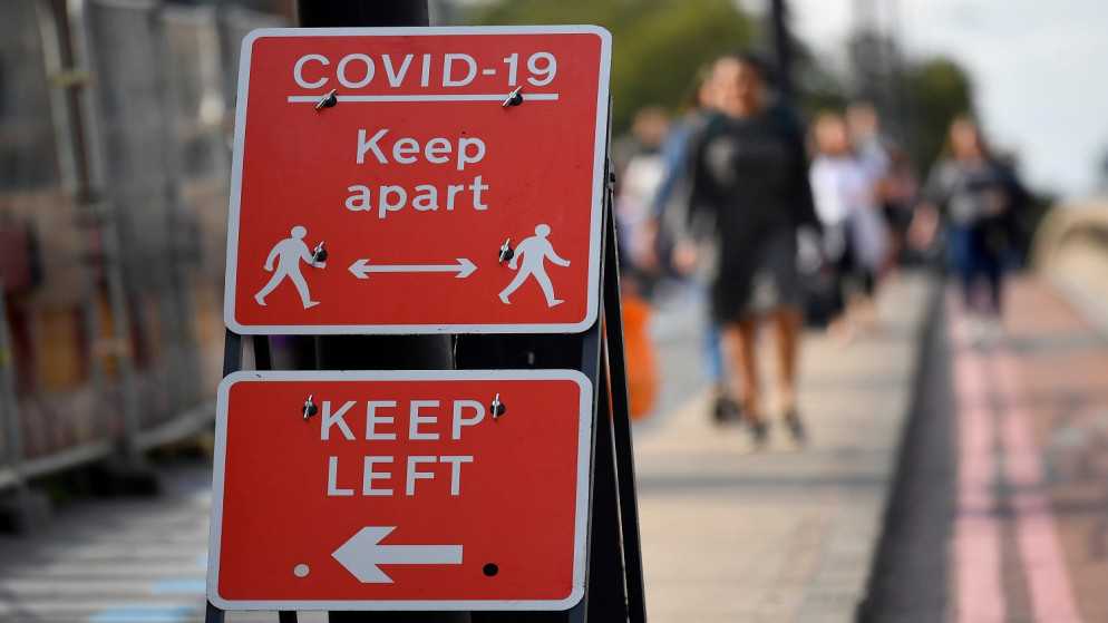 مشاة يسيرون بالقرب من لافتات الصحة العامة في لندن ، بريطانيا ، 11 سبتمبر / أيلول 2020. (رويترز / توبي ميلفيل)