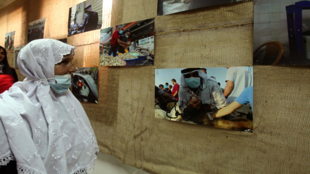 امرأة تقف أمام صورة في معرض صور فلسطيني بعنوان "كورونا بعدتنا وغيرت حياتنا" . (وفا)
