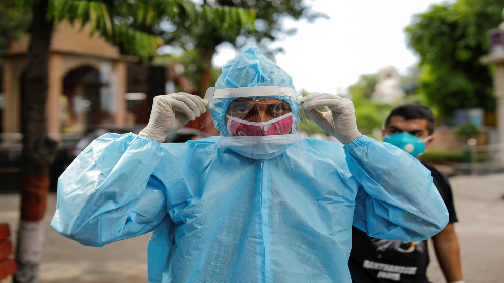 شخص يرتدي معدات حماية في نيودلهي بالهند قبل حرق جثة رجل توفي جراء إصابته بفيروس كورونا المستجد. (أ ف ب)